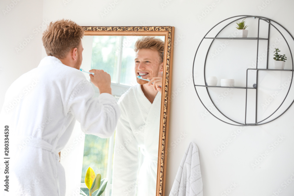 Morning of young man brushing teeth in bathroom