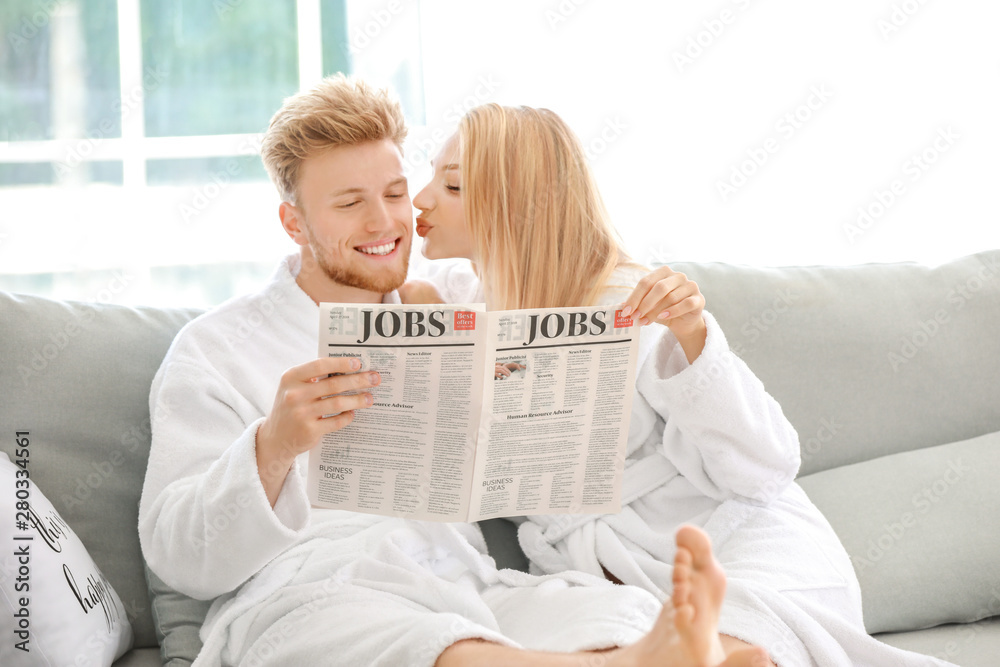 Morning of happy young couple reading newspaper at home