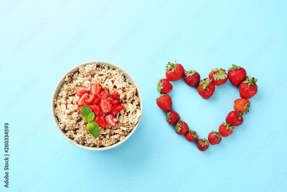 Bowl with tasty sweet oatmeal and strawberry on color background