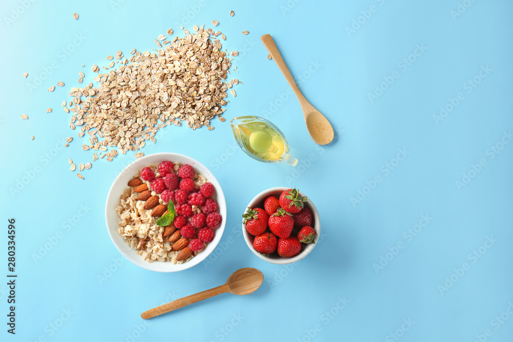 Bowl with tasty sweet oatmeal, honey and berries on color background