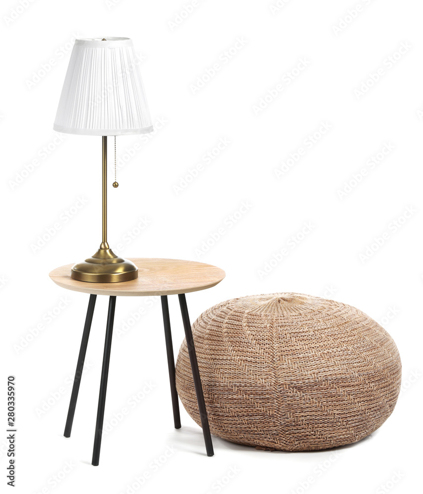 Table with lamp and pouf on white background