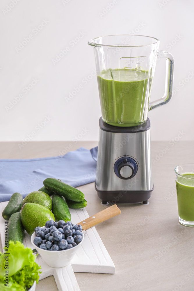 Blender with healthy smoothie and ingredients on table