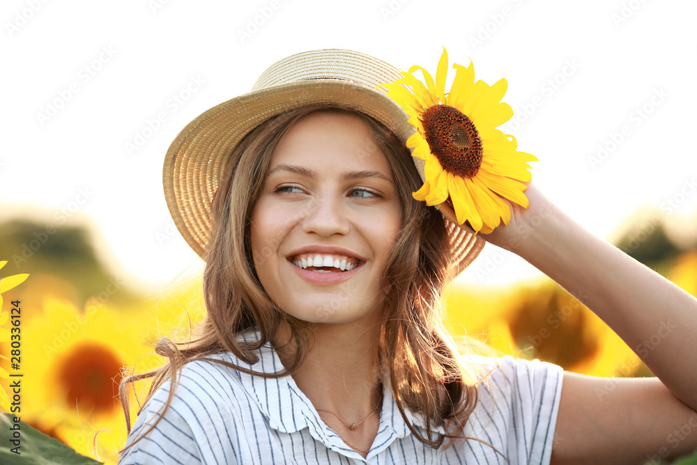 Beautiful young woman in sunflower field on summer day