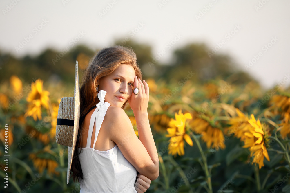 Beautiful young woman in sunflower field on summer day