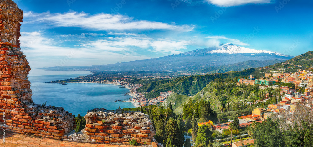 Ruins of ancient Greek theater in Taormina and Etna volcano in the background.