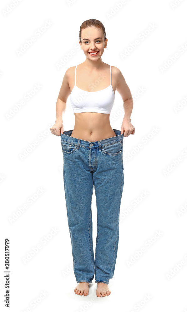 Young woman in loose jeans on white background. Weight loss concept