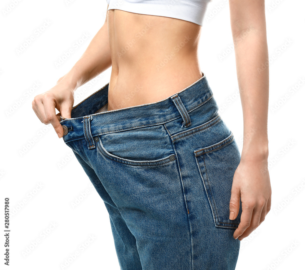 Young woman in loose jeans on white background. Weight loss concept