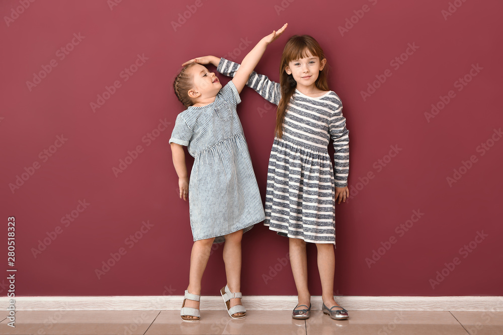 Little girls measuring height near wall