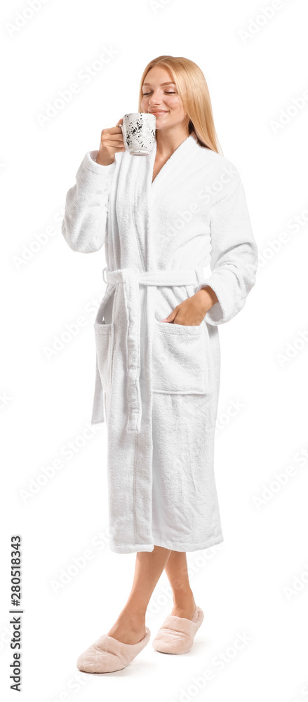 Beautiful young woman in bathrobe drinking coffee on white background