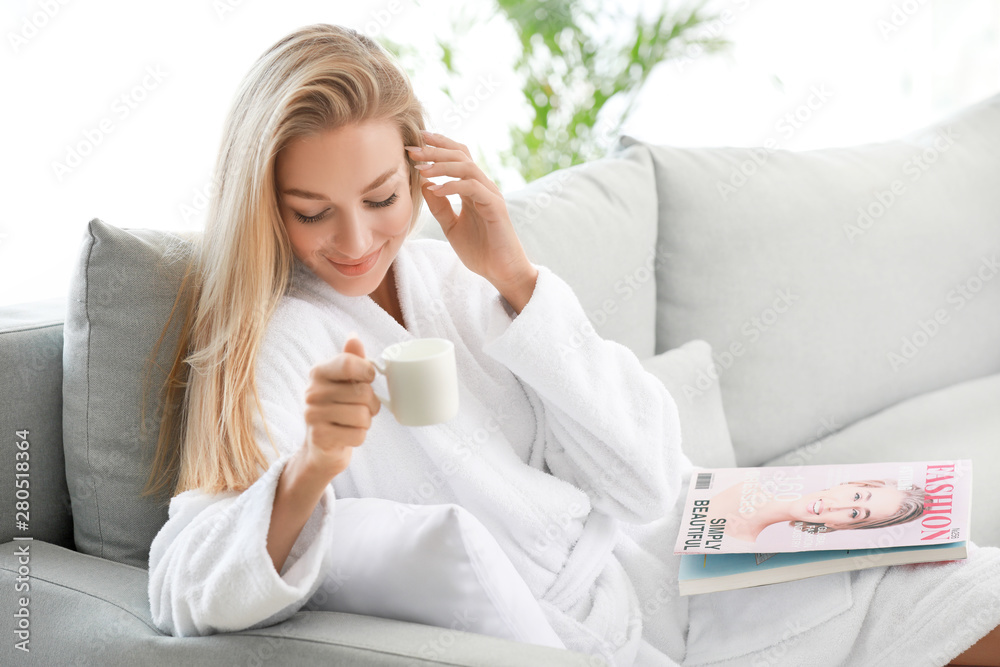 Morning of young woman drinking coffee while reading magazine at home