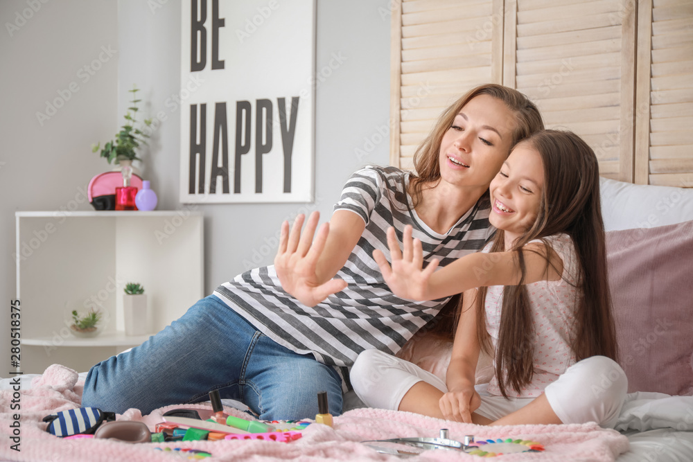 Cute daughter with mother making manicure at home