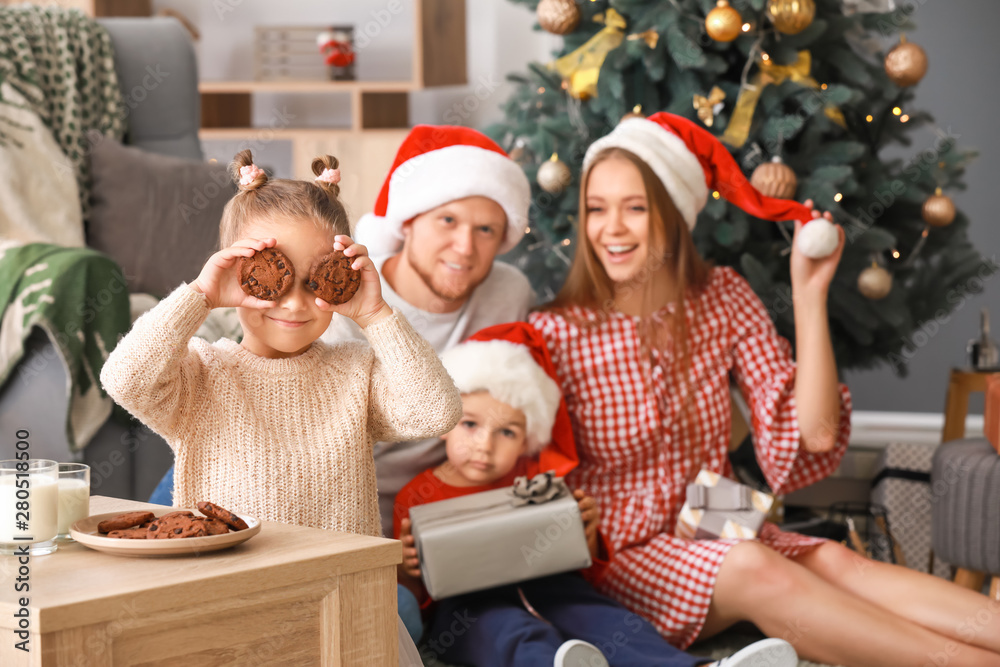 Little girl with tasty cookies and her family at home on Christmas eve