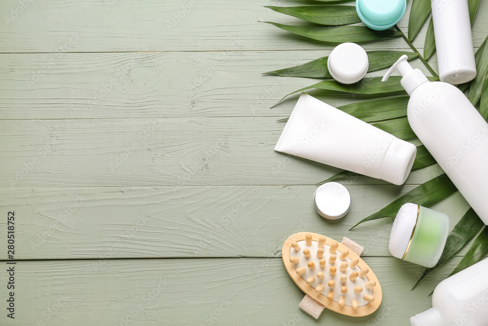 Set of cosmetic products and palm leaf on wooden background