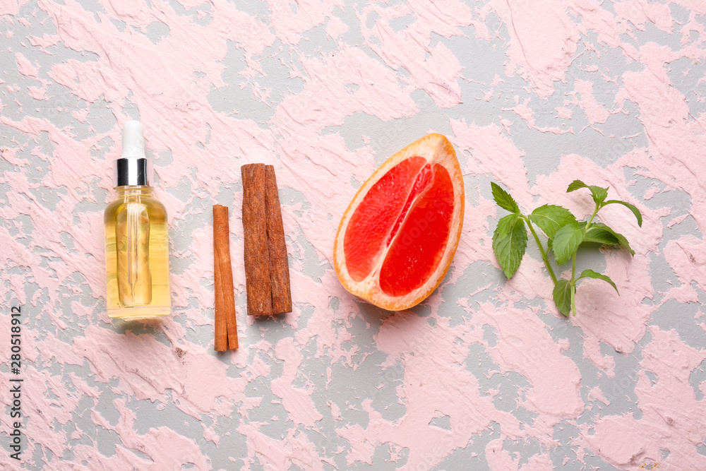 Citrus essential oil, cinnamon and grapefruit on color background