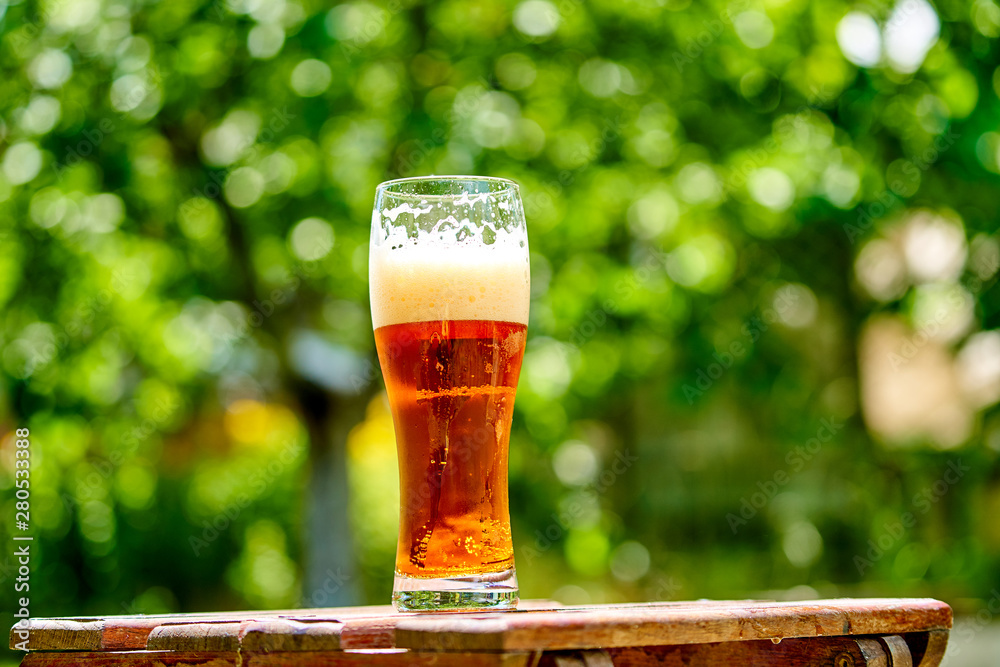 cold light beer with bubbles in a glass and dripping condensate drops