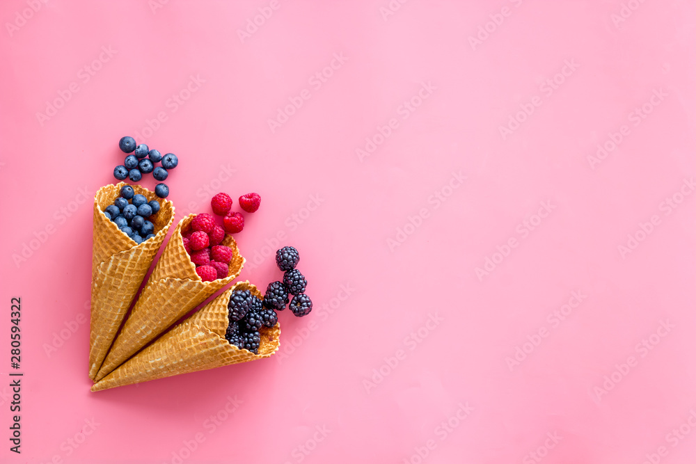 Fresh berries in waffle cones on pink background top view mock up