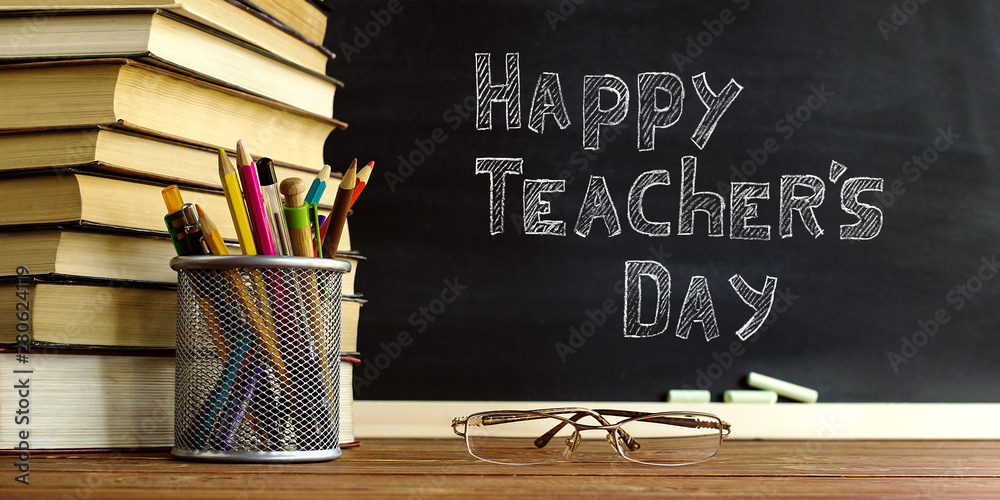 Glasses teacher books and a stand with pencils on the table, on the background of a blackboard with 