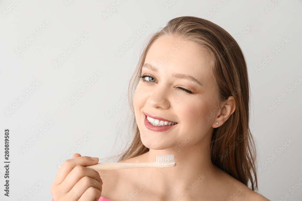 Happy woman with toothbrush on light background