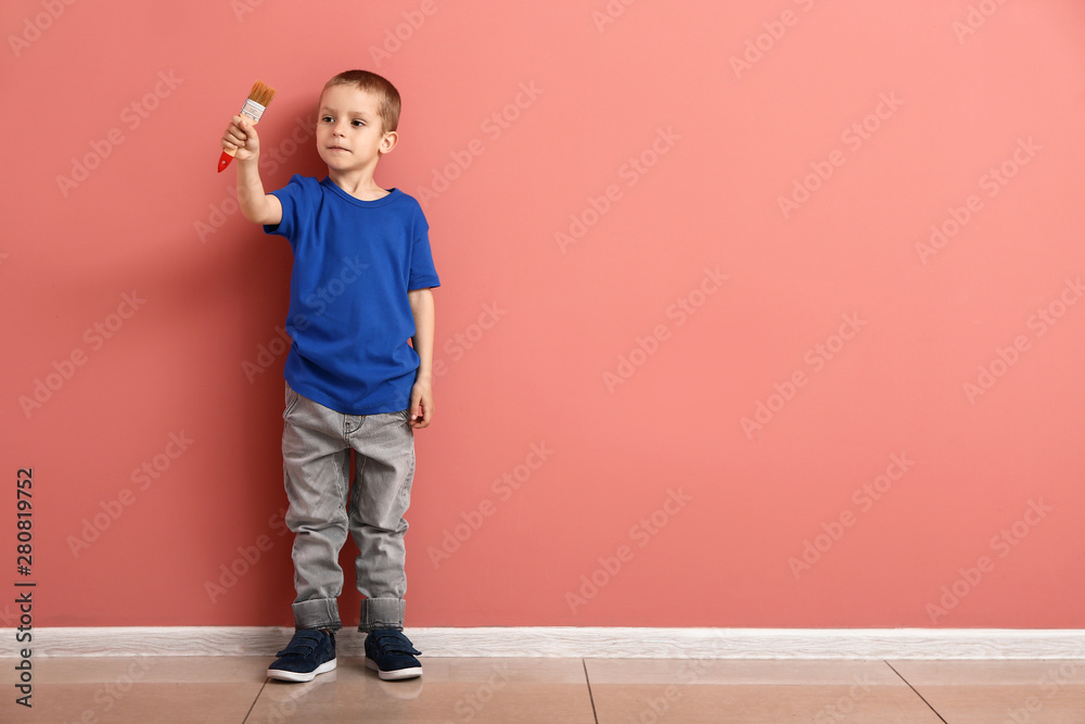 Little boy with brush near color wall