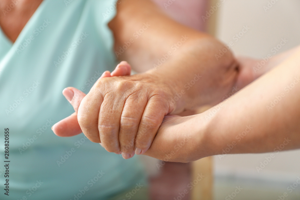 Young daughter supporting elderly mother at home, closeup