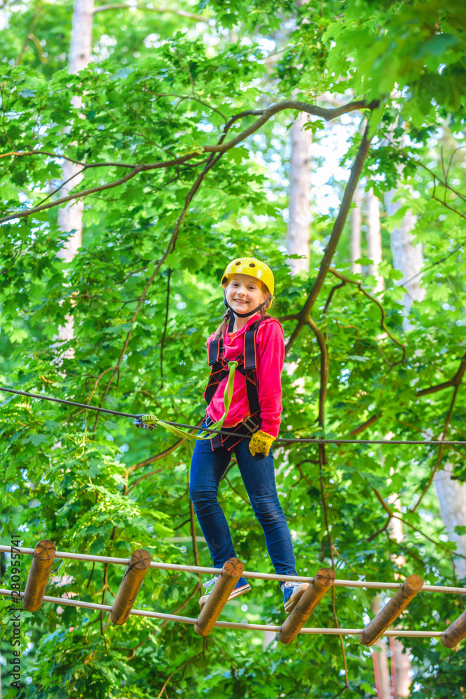 美丽的小孩在冒险公园登山并玩得很开心。在绳索公园徒步旅行的女孩在sa