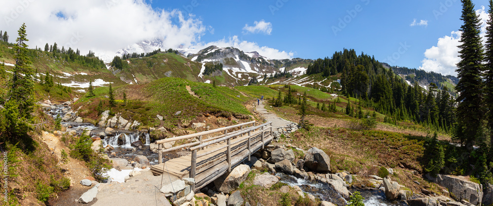 河流上的一条小径和一座桥的全景，周围环绕着山脉景观。