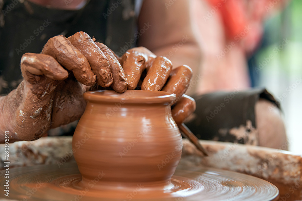 Potter makes pottery dishes on potters wheel