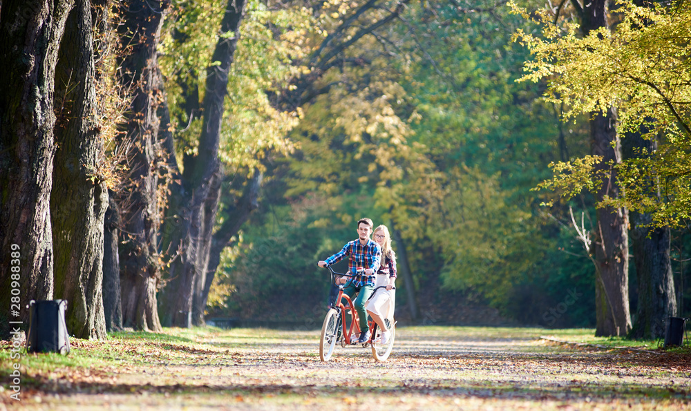 Young tourist couple, handsome bearded man and attractive blond long-haired woman cycling together t