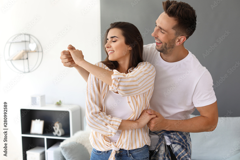 Happy young couple dancing at home