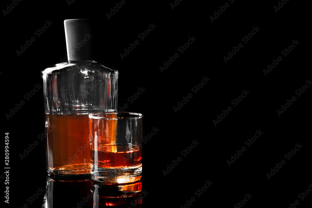 Glass and bottle of whiskey on dark background