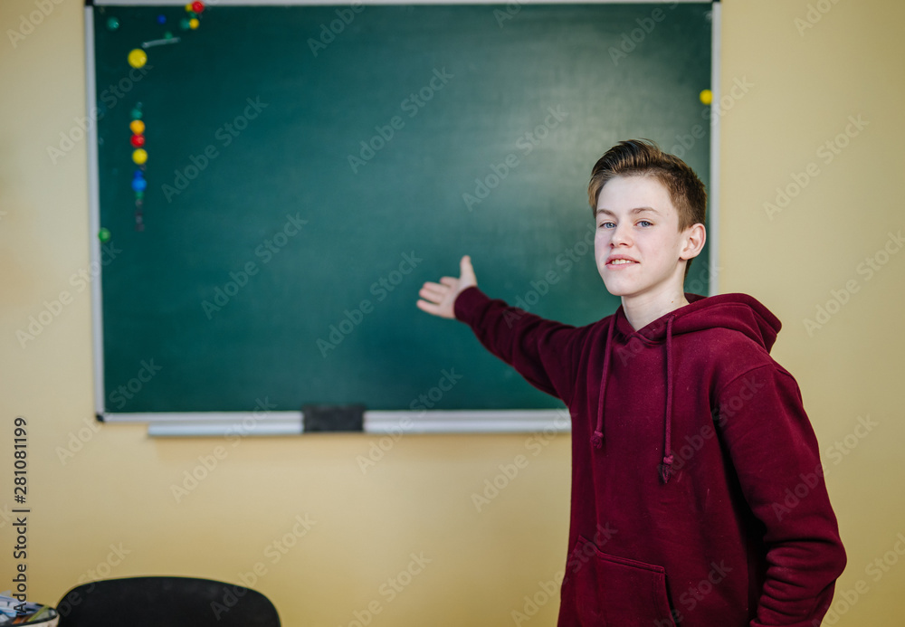 回到学校。英俊的年轻男学生靠着黑板站的肖像