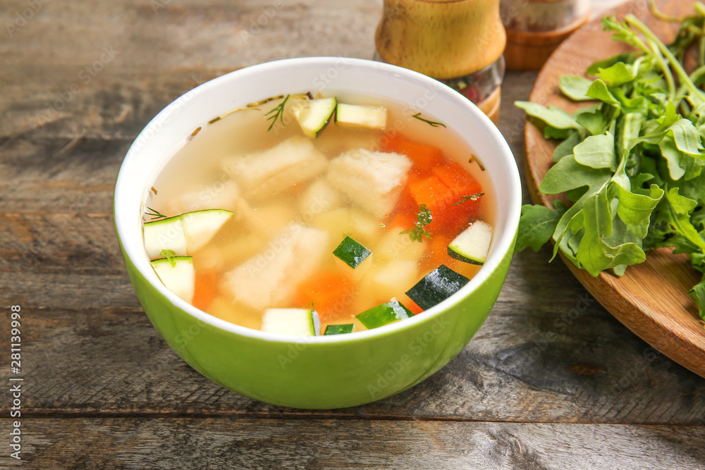 Bowl of tasty soup on wooden table