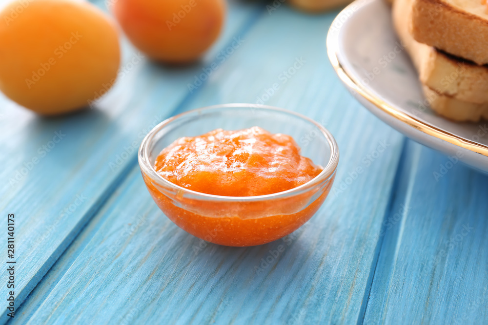 Bowl of tasty apricot jam on table