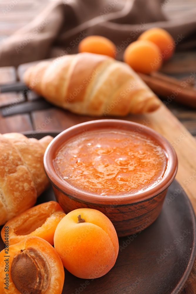 Bowl of tasty apricot jam on table, closeup