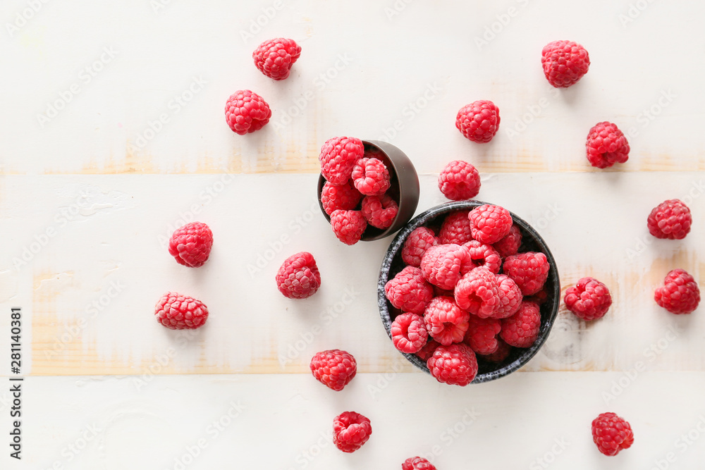 Bowls with fresh raspberries on white table