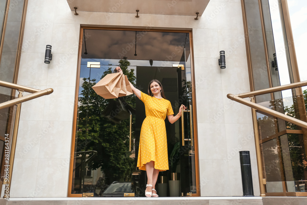 Beautiful woman with bags near shop entrance