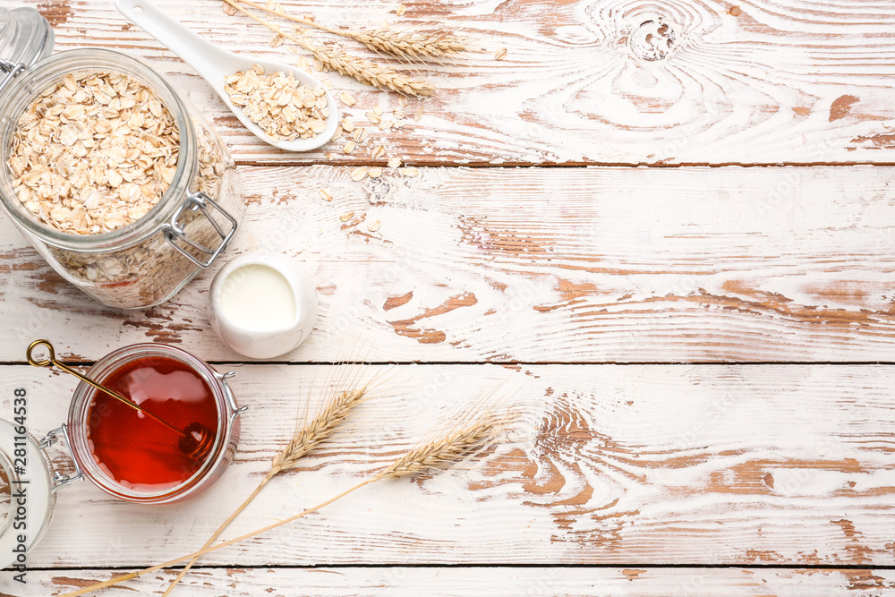 Jar with raw oatmeal, honey and milk on wooden table