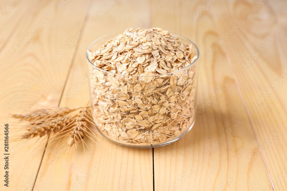 Container with raw oatmeal on wooden table