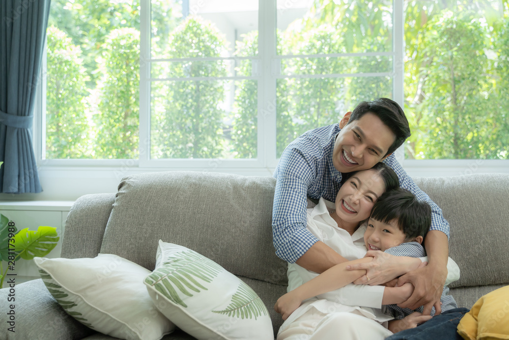 happy asian family spending time together on sofa in living room. family and home concept