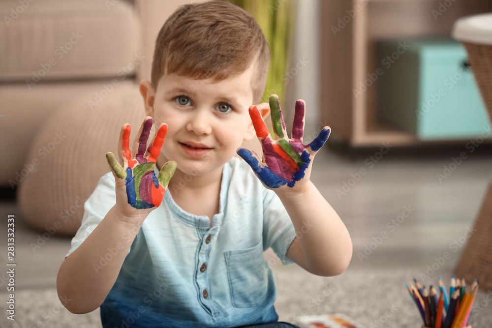 Cute little boy with hands in paint at home