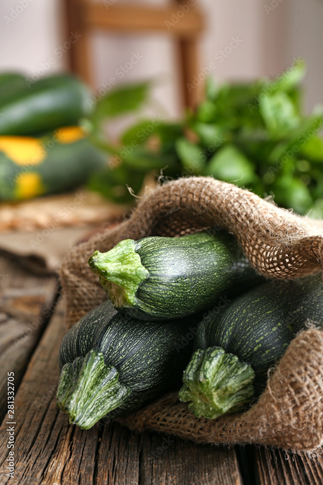 Bag with fresh zucchini on wooden table