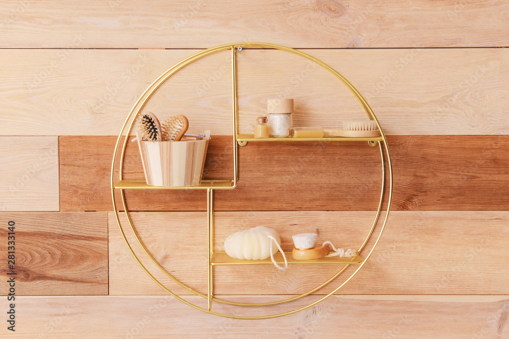 Stylish shelf with bath supplies on wooden wall