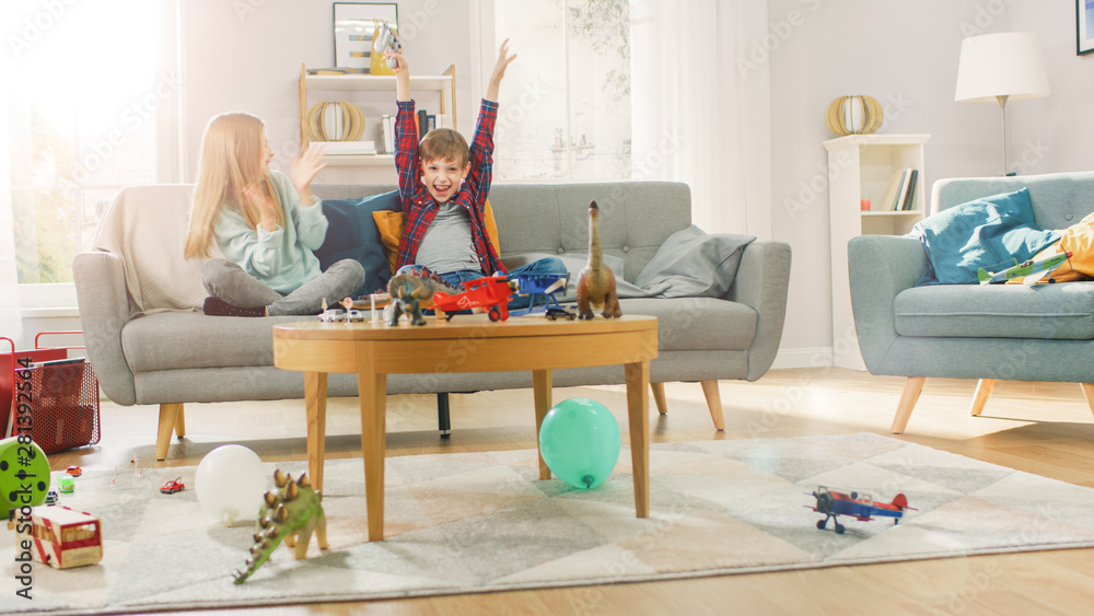 At Home: Smart Boy Playing in Video Game Console, Using Joystick Controller, His Older Sister Sits N