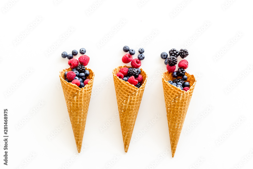 Summer breakfast with fresh berries in waffle cones on white background top view