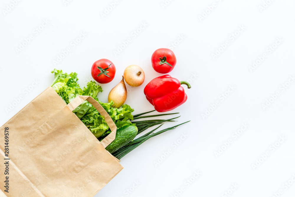 Healthy food with fresh vegetables in paper bag on white background top view