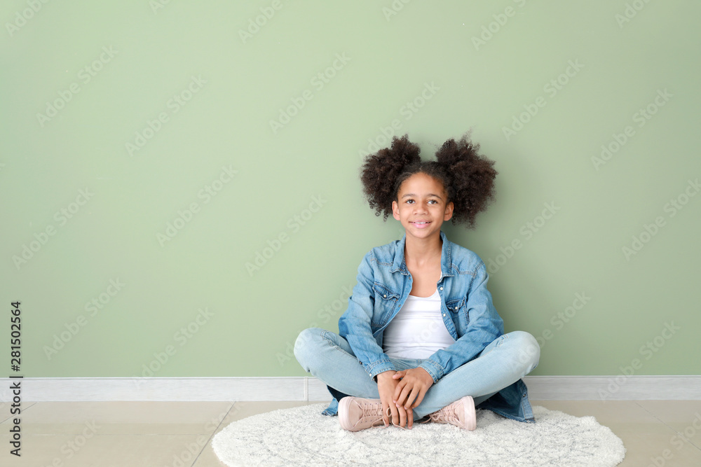 Stylish African-American girl in jeans clothes near color wall