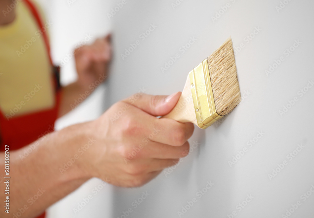 Male decorator painting light wall, closeup