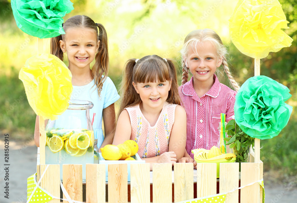 Cute little children selling lemonade in park