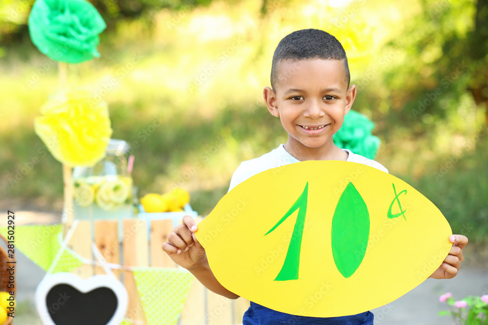 Cute little African-American boy selling lemonade in park