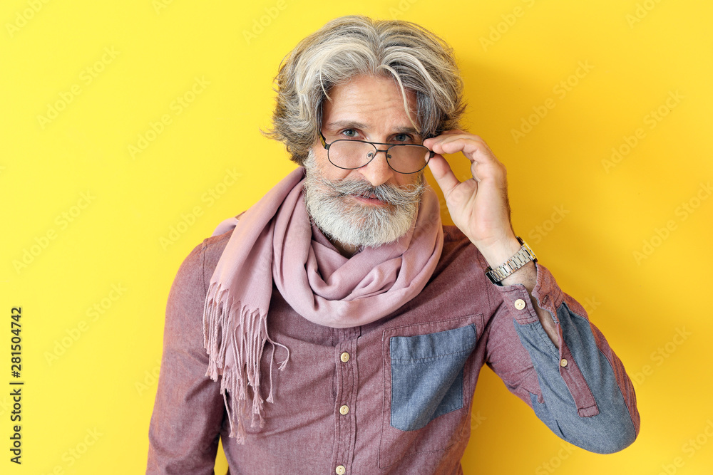 Fashionable senior man on color background